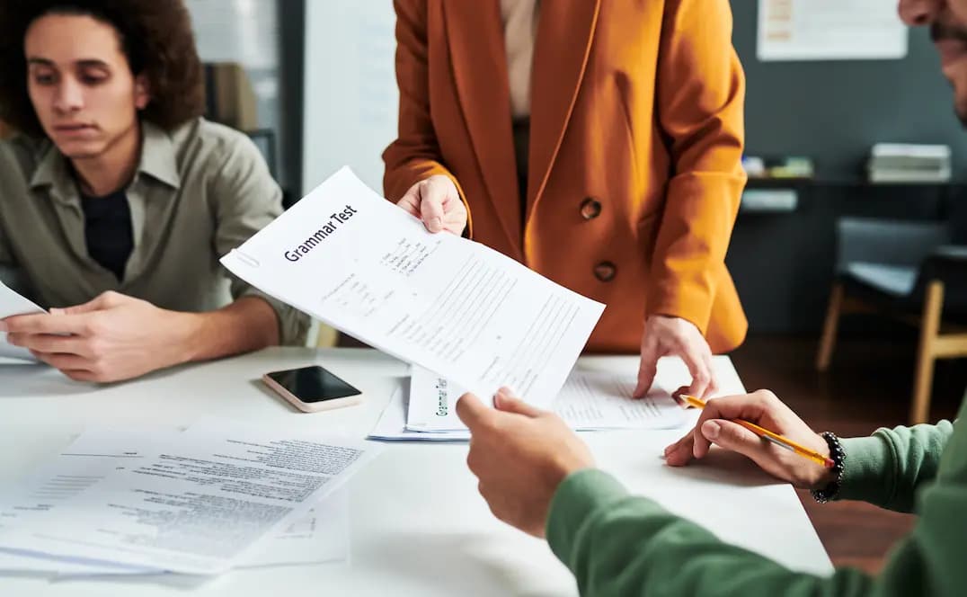 Studenti riuniti attorno a un tavolo per una sessione di studio, analizzando un test di grammatica.