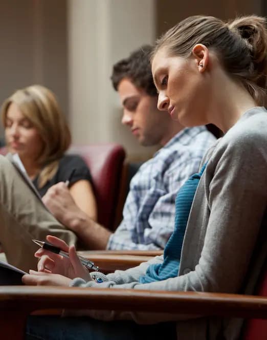 Studenti concentrati che prendono appunti durante una lezione in aula universitaria.